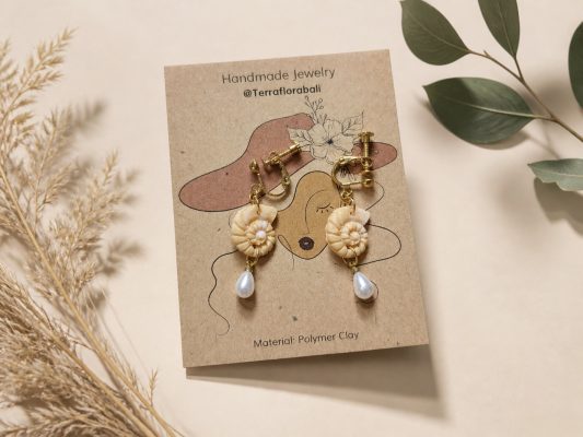 Gold clip-on hoop earrings with a cream clay ammonite shell and a white teardrop pearl